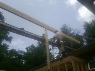 Carpenter setting a ridge beam over a new addition frame — Ice Dam Removal by Roofing Brothers in Mc Intire