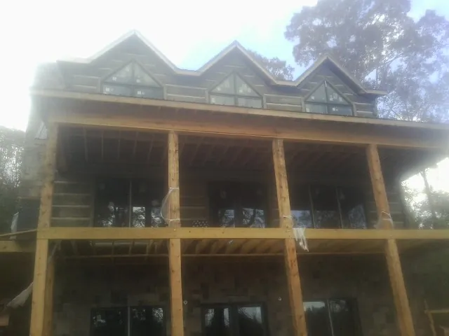 Dormers and porch framing on a large log home under construction — Roof Coating work by our crew in Mc Intire