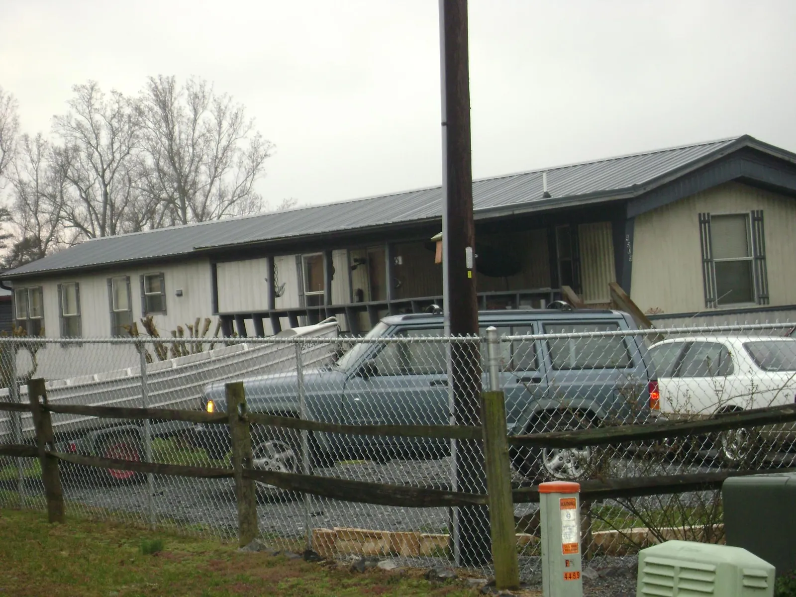 Dark metal roof on a long single story building behind a chain link fence in Mc Intire