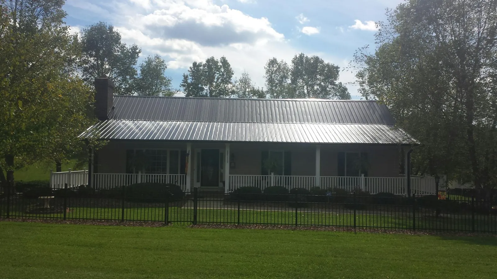 Gray metal roof on a brick ranch with a full width front porch — Gutter Guard Installation work by our crew in Mc Intire