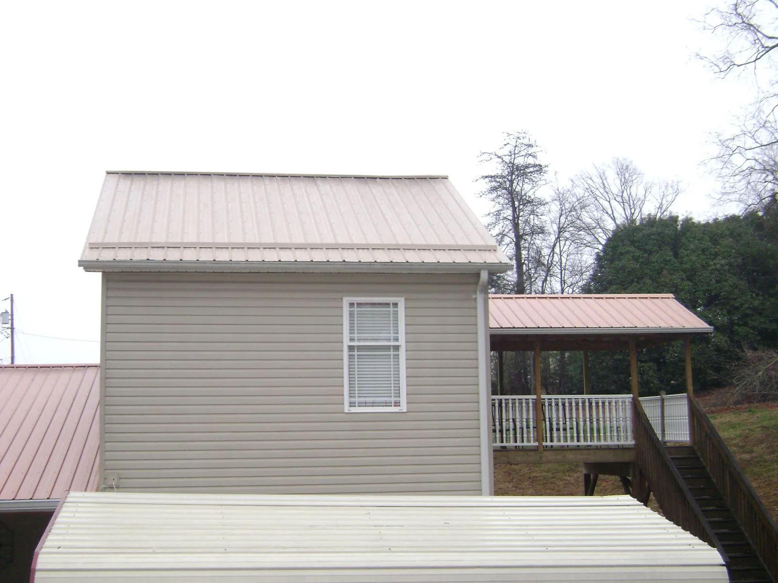 Tan metal roofs on a two story addition and attached porch, from a Roof Replacement job in Mc Intire