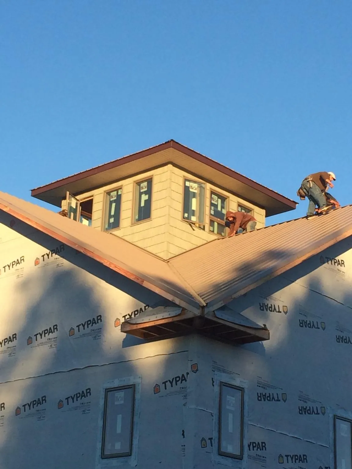 Roofers working around a rooftop cupola on a new metal roof at sunset — Roof Waterproofing in Mc Intire by Roofing Brothers